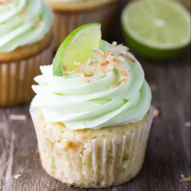 Coconut cupcakes topped with lime buttercream frosting on a decorative plate.