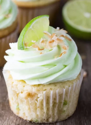 Coconut cupcakes topped with lime buttercream frosting on a decorative plate.