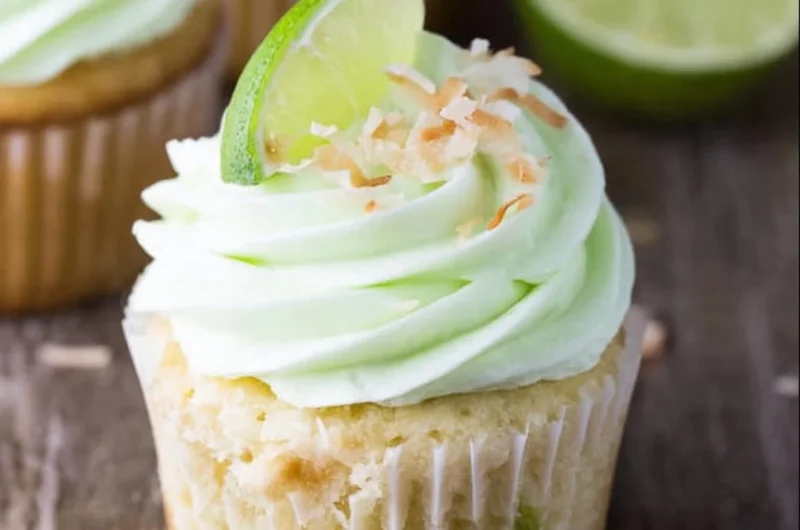 Coconut cupcakes topped with lime buttercream frosting on a decorative plate.