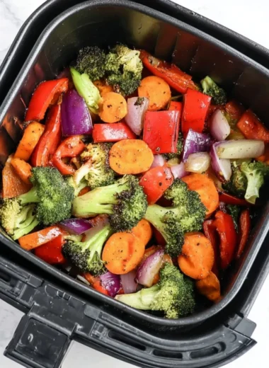 Bowl of easy air fryer roasted vegetables featuring colorful peppers, carrots, and zucchini.