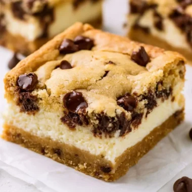 Delicious chocolate chip cheesecake bars topped with chocolate chips and a creamy filling.