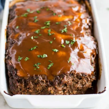 Delicious classic meatloaf served with brown gravy on a plate.