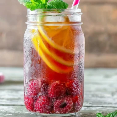 Glass of Earl Grey Raspberry Iced Tea with fresh raspberries and lemon slices.
