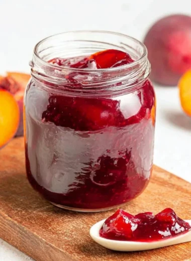 Homemade easy plum jam in a jar with ripe plums on the side