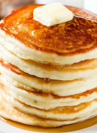 Delicious fluffy pancakes stacked on a plate with syrup and berries