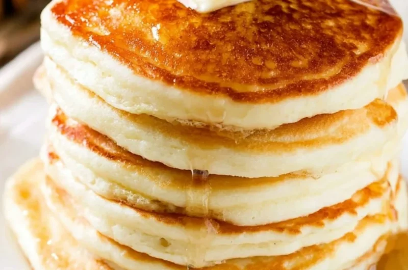 Delicious fluffy pancakes stacked on a plate with syrup and berries
