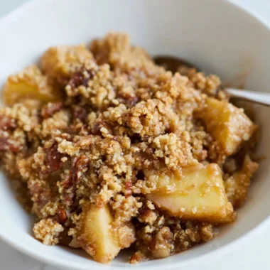 Healthy breakfast apple crumble topped with nuts and fruits on a plate.