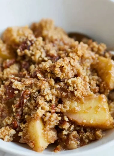 Healthy breakfast apple crumble topped with nuts and fruits on a plate.