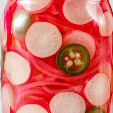 Quick pickled radishes in a jar, perfect for adding flavor to various dishes.