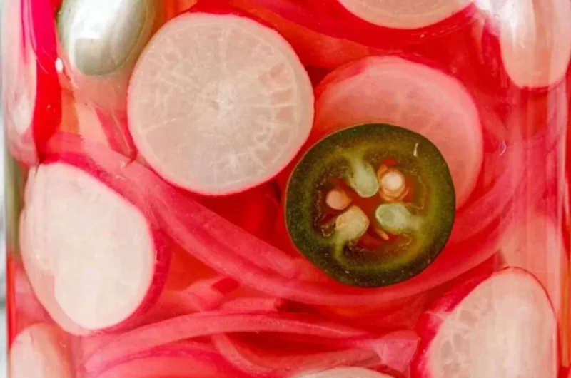 Quick pickled radishes in a jar, perfect for adding flavor to various dishes.