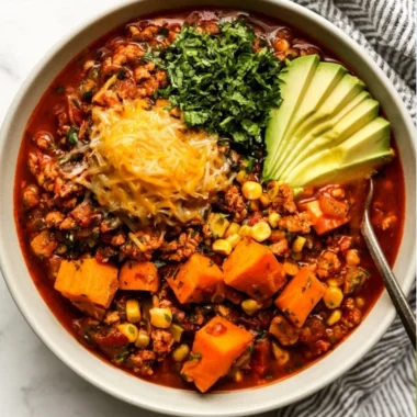 Bowl of hearty sweet potato turkey chili topped with cilantro and avocado.