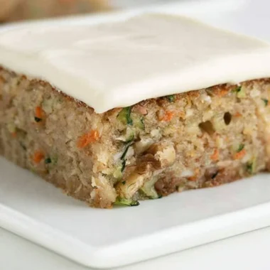 Delicious homemade zucchini bars topped with frosting and served on a plate