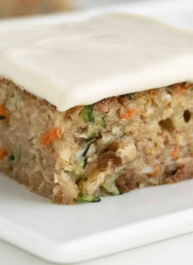 Delicious homemade zucchini bars topped with frosting and served on a plate