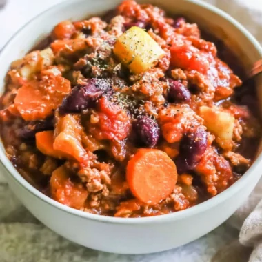 Bowl of Turkey Apple Chili garnished with fresh herbs and served with crusty bread