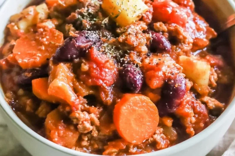 Bowl of Turkey Apple Chili garnished with fresh herbs and served with crusty bread