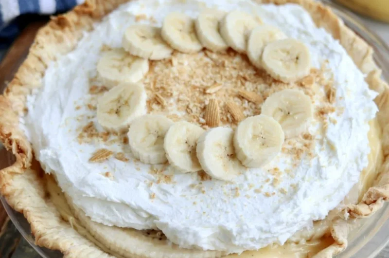Slice of delicious Banana Cream Pie with whipped cream and fresh bananas