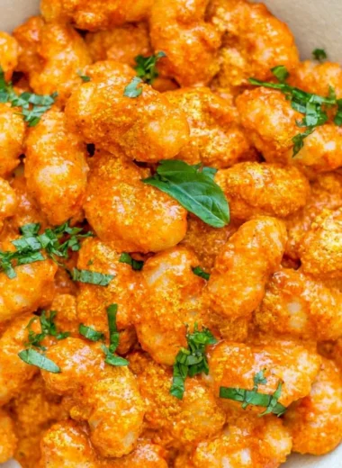 Cozy gnocchi in garlic cream tomato sauce served in a bowl garnished with herbs.