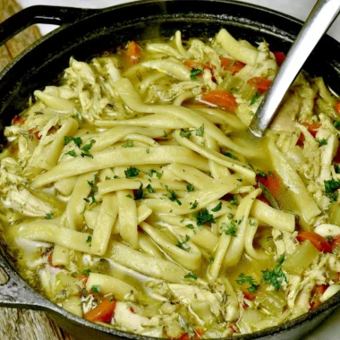Bowl of cozy homemade chicken noodle soup with fresh vegetables and herbs