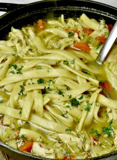 Bowl of cozy homemade chicken noodle soup with fresh vegetables and herbs