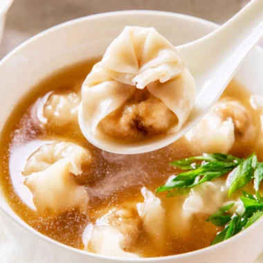 Bowl of cozy wonton soup with dumplings and fresh herbs