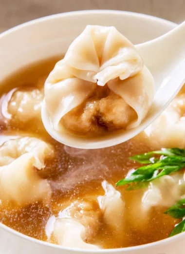 Bowl of cozy wonton soup with dumplings and fresh herbs