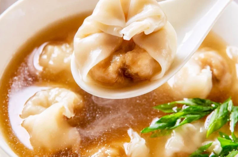 Bowl of cozy wonton soup with dumplings and fresh herbs