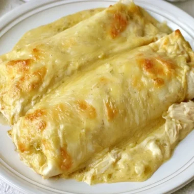 Creamy white chicken enchiladas topped with sauce and cheese