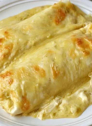 Creamy white chicken enchiladas topped with sauce and cheese