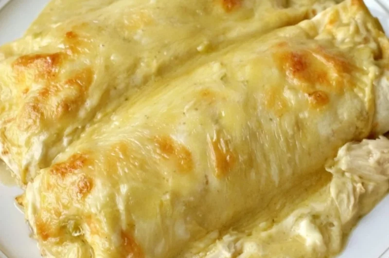 Creamy white chicken enchiladas topped with sauce and cheese