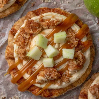 Crumbl caramel apple cookies topped with caramel drizzle and apple pieces