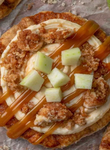 Crumbl caramel apple cookies topped with caramel drizzle and apple pieces