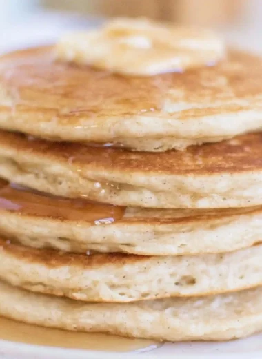 Fluffy sourdough pancakes topped with syrup and berries on a plate