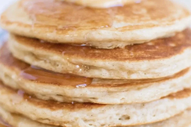 Fluffy sourdough pancakes topped with syrup and berries on a plate