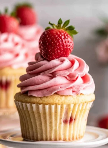 Delicious strawberry jam cupcakes topped with fresh frosting and berries.