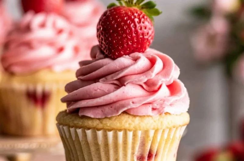 Delicious strawberry jam cupcakes topped with fresh frosting and berries.