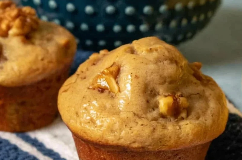 Freshly baked banana nut muffins with walnuts on a cooling rack